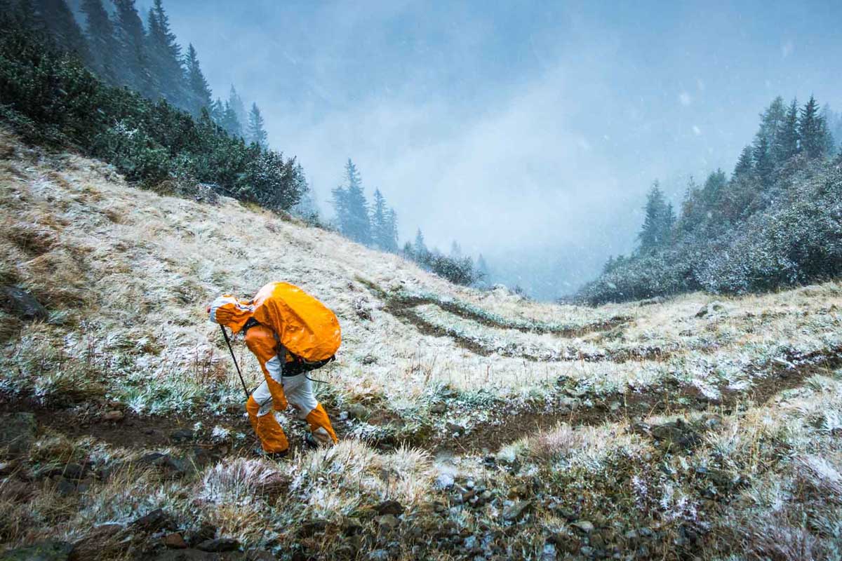 Man wearing backpacking backpack with rain cover in snowy conditions